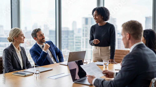 Fotografie Diverse business professionals holding a dynamic meeting and presentation in a modern conference room with city views