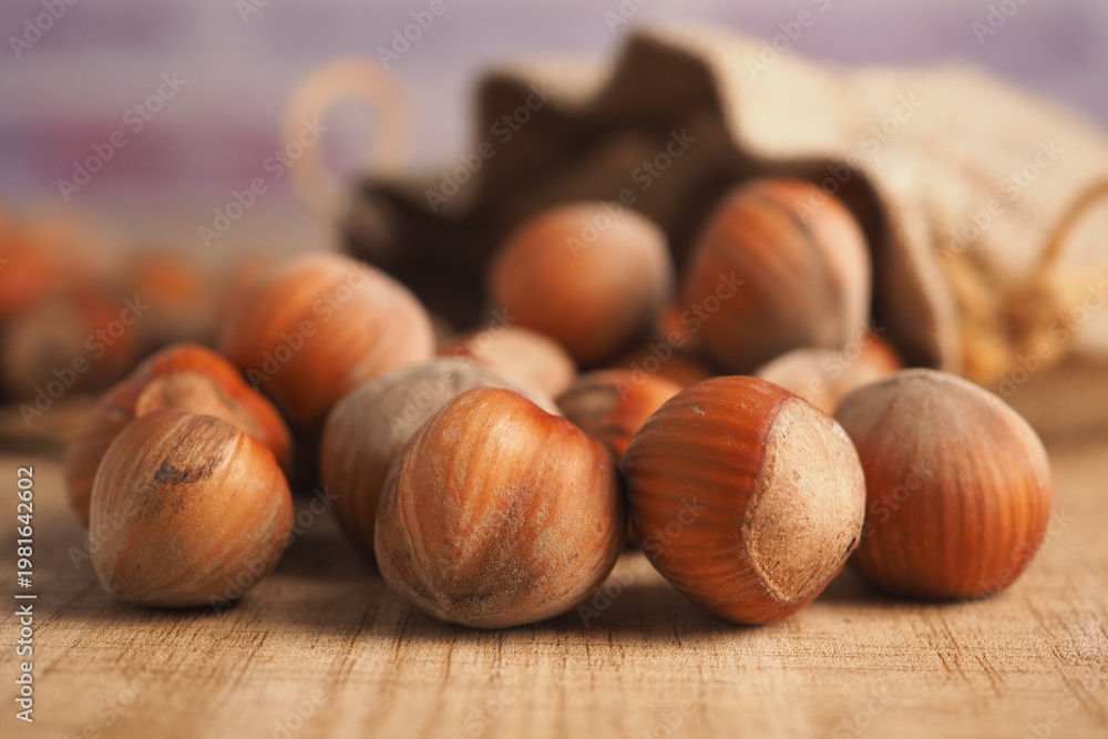 Obraz premium Hazelnuts on a wooden table with a cloth bag nearby