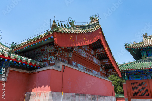 The image captures the intricate green glazed tiles, traditional roof ornaments, and vibrant red walls of a historic building within the Temple of Heaven complex in Beijing, China 28 May 2025