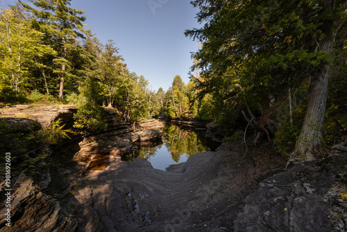 River flowing through narrow rock gorge with forest reflection