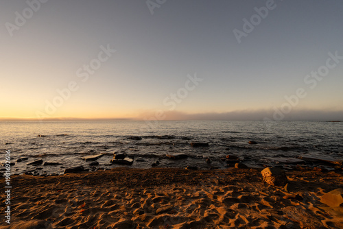 Golden hour light illuminating Lake Superior shoreline misty horizon