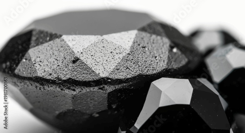 Close-up view of rough black faceted gemstones with a textured surface, showcasing their unique geometric cuts and dark appearance.