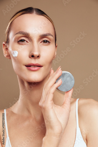 woman face skincare beauty cotton pad closeup portrait, applying gentle cleanser on cheek, calm expression, smooth skin, soft studio light, beige background