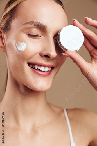 Woman skincare facial cream moisturizer beauty mirror smile treatment spa, close up portrait, woman applies eye cream with fingers, eyes closed, soft studio light