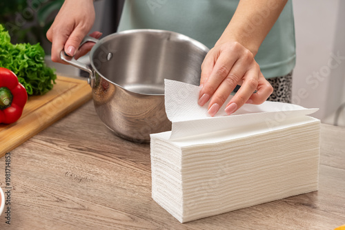 Woman cleans stainless pot using kitchen paper towel. Close-up. Fingers holding a tissue paper Lifestyle. Photo