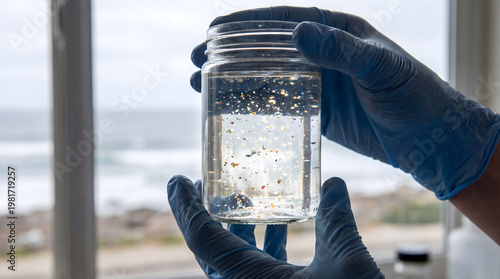 Scientist hands holding jar of microplastic water sample