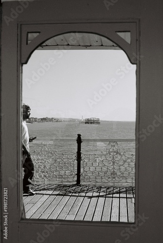 Black and White View Through Archway of Man Standing on Brighton Pier