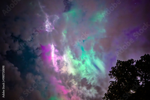 Northern öights dancing behinde the dark cloud over country landscape