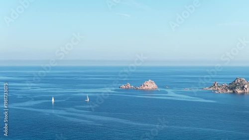 Aerial drone view of Santa Maria Navarrese, featuring turquoise waters, sandy beaches, marina harbor and dramatic limestone mountains along the eastern Sardinian coastline on a sunny day.