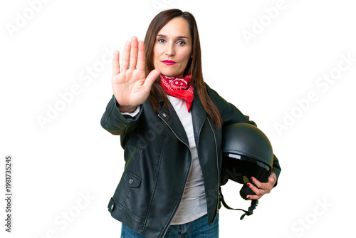 Middle age caucasian woman with a motorcycle helmet over isolated chroma key background making stop gesture