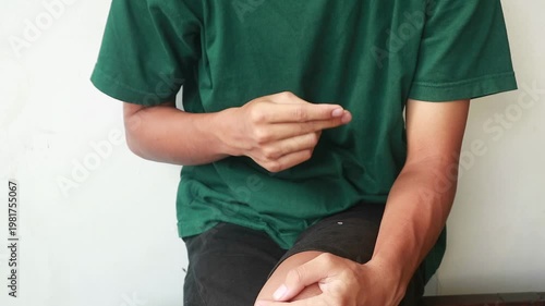 Close-up of a person sitting and fingering against a plain white background