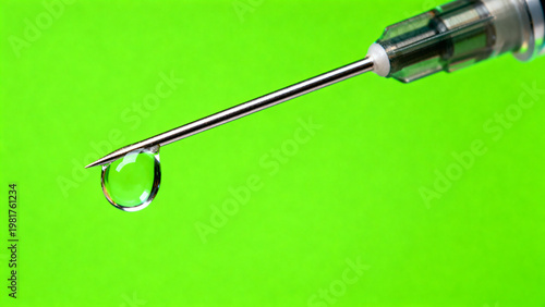 Extreme macro photography of a sharp medical steel syringe needle with a single clear vaccine droplet hanging on the tip isolated on a solid bright chroma key green screen background for ads