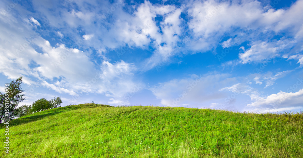 Obraz premium Vibrant green hill rises beneath wide blue sky