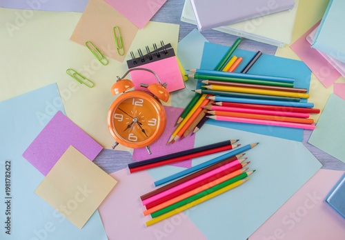 Flat lay colorful alarm clock and stationery and office supplies. Concept of learning, back to school.