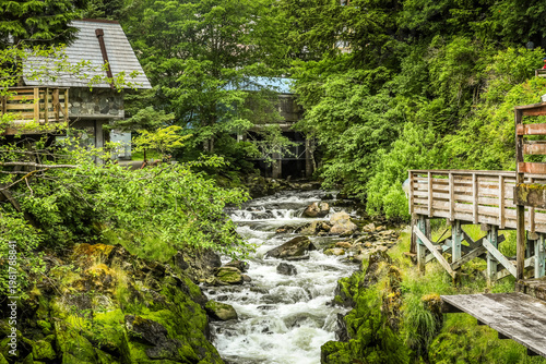 Rushing forest stream flowing through rustic downtown Ketchikan with wooden walkways and cabins