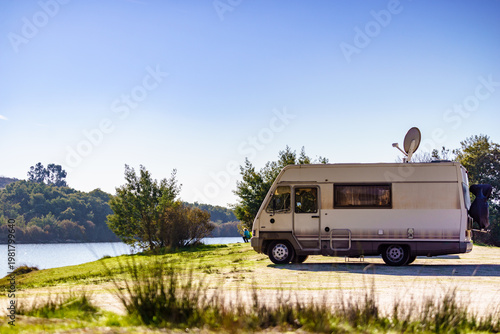 Caravan camping on lake shore with satellite dish on roof