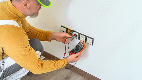Electrical installation. The electrician's hands measure the voltage in an electrical outlet using a multimeter during installation a wall multi pack socket.