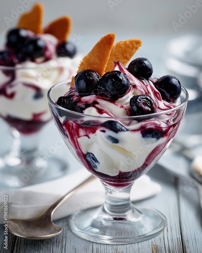 Vertical close up of a layered berry parfait in a glass. Yogurt dessert with blueberry sauce and crisp wafers on a wooden table