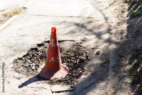 Indication of neglect in urban infrastructure with warning cone and cracked surface