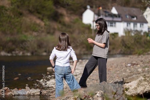 Children interacting by river in natural setting. Concept of shared experience