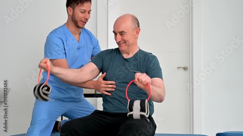 Adult patient with disability performing strength exercises using light weights assisted by physiotherapist. Rehabilitation, mobility improvement, motor skills and recovery in healthcare clinic. 