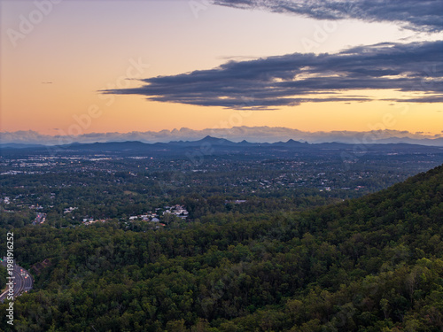Bild auf Leinwand Breathtaking twilight panorama of Brisbane city, its sprawling suburbs, and distant mountains under a radiant sunset sky