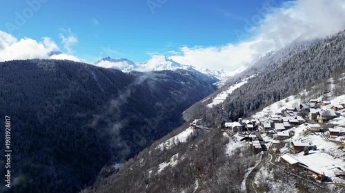 Snow covered alpine village in Tarentaise Valley with traditional houses and mountain scenery in the French Alps, Savoie, France.