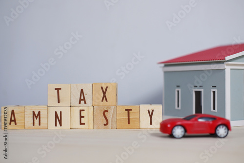 Foto Tax amnesty writing and miniature cars and houses.
