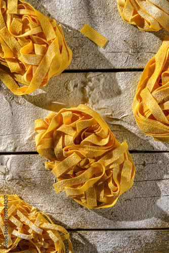 raw fettuccine on a wooden table with flour