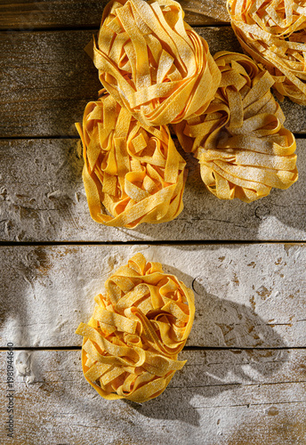 raw fettuccine on a wooden table with flour