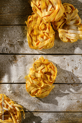 raw fettuccine on a wooden table with flour
