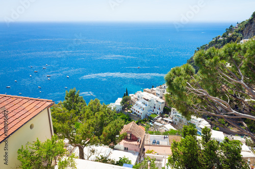 Picturesque Positano on Amalfi Coast Italy with terraced buildings, pine trees, and blue Mediterranean sea under clear sky. Welcome to Positano concept photo