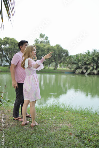 Asian Woman Pointing at Scenic Lake View with Partner