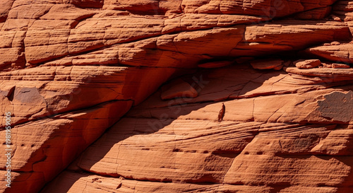 Detailed close-up macro texture of stratified red sandstone rock face with dramatic light and shadow creating natural abstract patterns and geological formations.