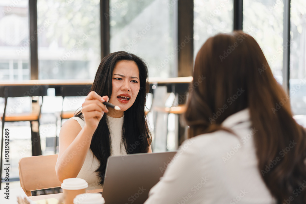 Fototapeta premium Angry business woman arguing with her colleague during a stressful meeting in a modern cafe workspace.