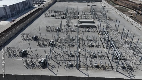 Aerial rotating pan of electrical substation powering data center, showing transformers, transmission lines, and industrial energy infrastructure in a secure facility.
