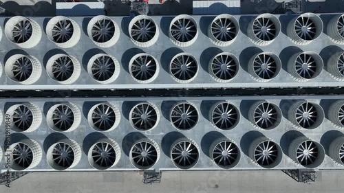 Aerial top-down of industrial cooling fans at a data center, some spinning. Lateral slide reveals grid symmetry and infrastructure supporting AI, cloud computing, and high-performance servers.
