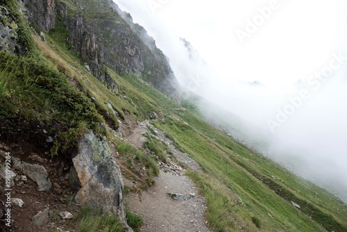 Mountain hiking trail disappearing into fog with scenic alpine landscape and adventure concept. Mont Blanc Monte Bianco Alps mountain in Europe