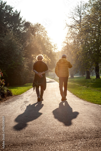 Elder couple enjoying a morning walk on a pathway with long shadows and warm light