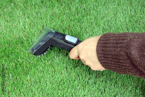 female hand holding a spot cleaner to clean artificial grass.