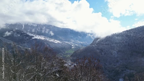 Aerial view of Tarentaise Valley with highway, alpine villages and snowy mountains covered in fog in the French Alps, Savoie, France.