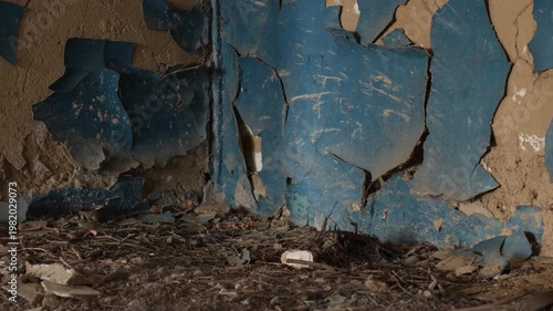 Close up of peeling blue paint on a decaying plaster wall in an abandoned derelict building interior
