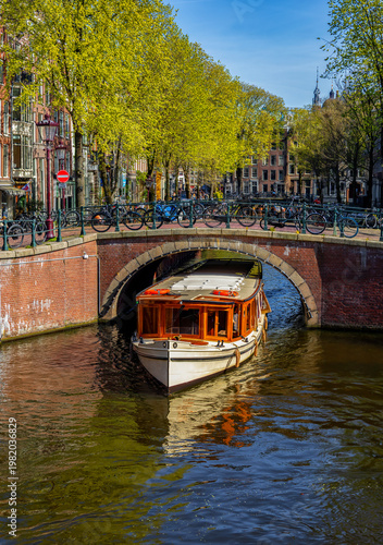 Tourist canal boat passing under a bridge, Jordaan neighbourhood, Amsterdam, Netherlands — canal cruise