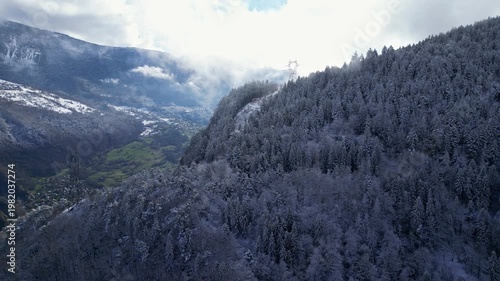 Aerial view of Tarentaise Valley with highway, alpine villages and snowy mountains covered in fog in the French Alps, Savoie, France.