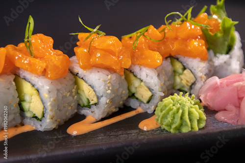 Obraz na plátne Delicious salmon sushi rolls with avocado and wasabi on black background