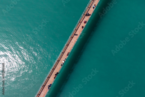 Aerial View of People Walking on Wooden Bridge Over Turquoise Water