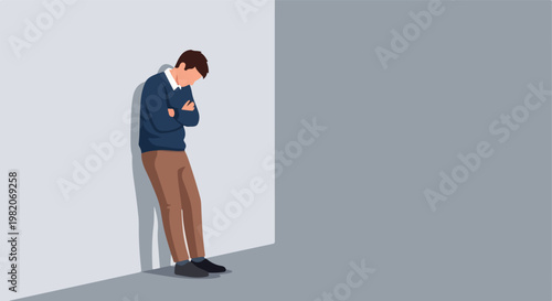 A man in a blue sweater and brown trousers leans against a plain gray wall