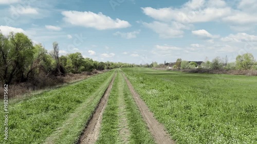 View from rider perspective on a bicycle along a dirt road across green countryside. Open landscape creates a freedom, travel and active lifestyle concept