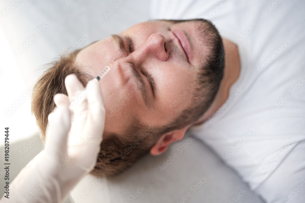 Fototapeta premium Cosmetic injection procedure on male forehead. Close-up of botox treatment for wrinkle reduction and anti-aging in modern aesthetic clinic.
