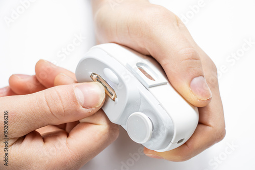 Canvas Print Close-up of hands using electric nail trimmer device with slot, gently filing fingernail length, safe manicure tool for home use, personal nail care concept